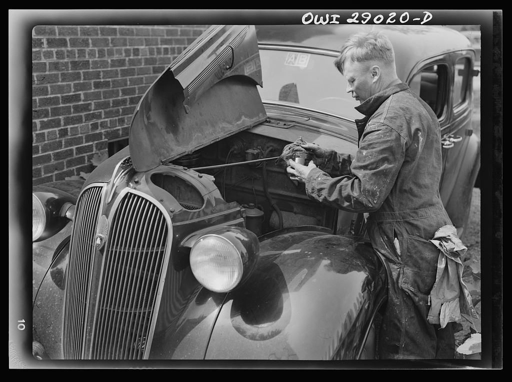 A man repairing his own automobile in a driveway, Silver Spring, Maryland, 1943